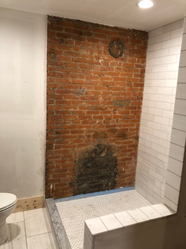 The exposed brick of this old fireplace will be part of the shower!
